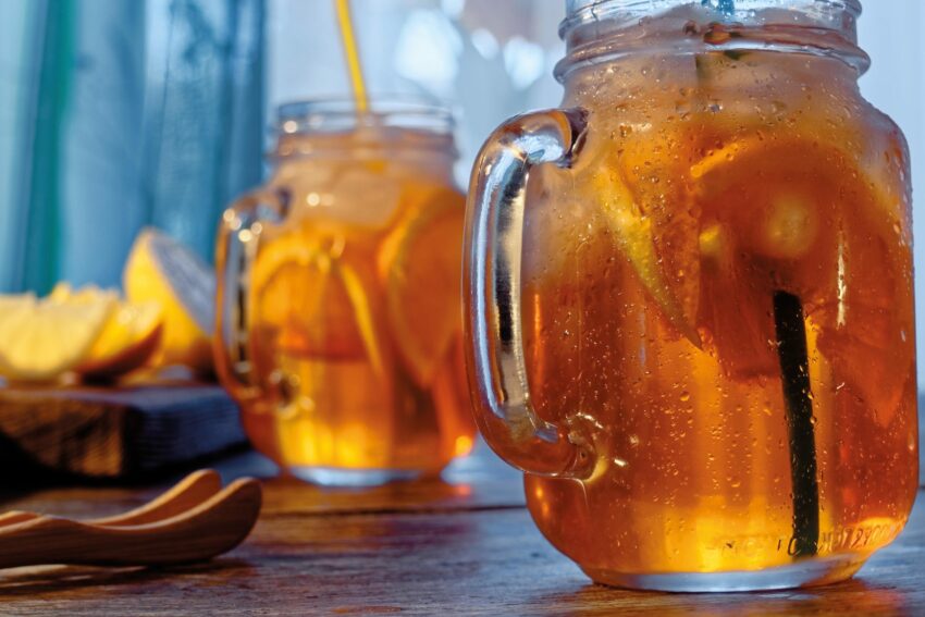 Iced black tea with orange and lemon slices served in mason jars. Close-up